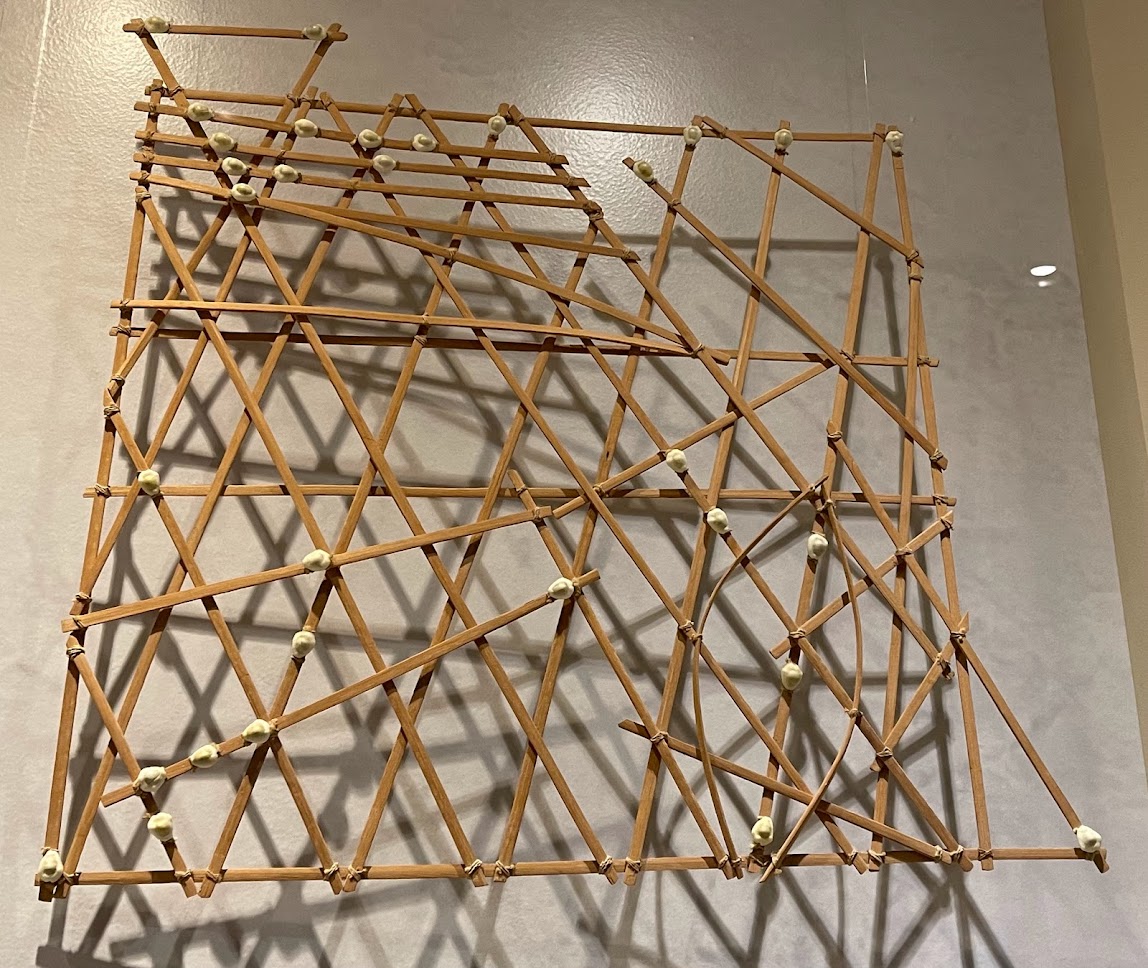 A non-square grid of wooden sticks with some material stuck to intersections.